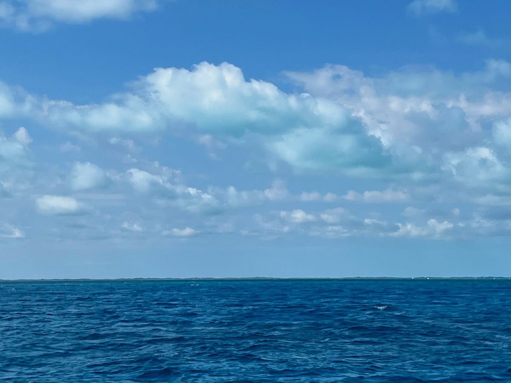 The shallow waters with white sand sometimes reflect the color of the water off the bottom of the clouds